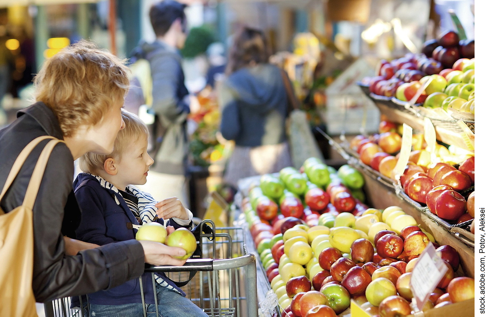 Mutter mit Kind im Supermarkt vor dem Apfelregal.